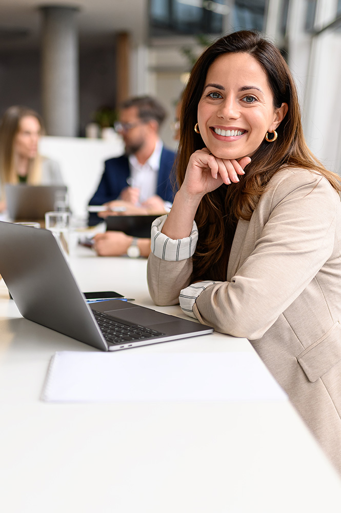 Frau arbeitet am Copmuter, dahinter ihre Teamkollegen